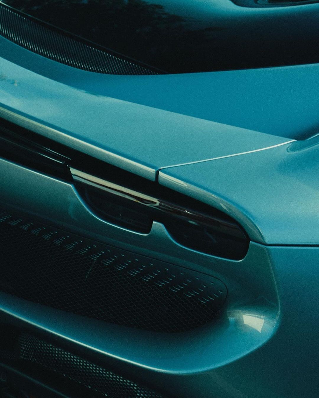Close-up shot of a teal-colored sports car featuring a visible grille and elegant, curving body design.