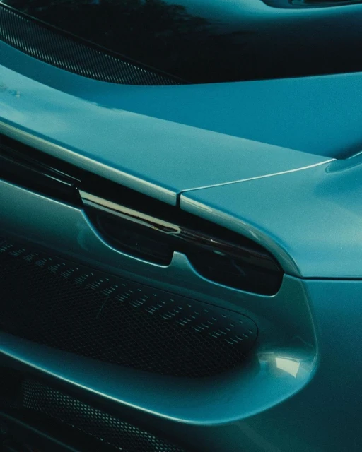 Close-up shot of a teal-colored sports car featuring a visible grille and elegant, curving body design.