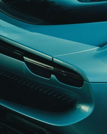 Close-up shot of a teal-colored sports car featuring a visible grille and elegant, curving body design.