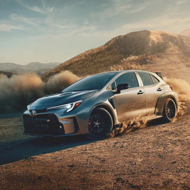 Silver Toyota GR Corolla hatchback speeds across a dirt road in a mountainous landscape, kicking up dust. Automotive product shot.