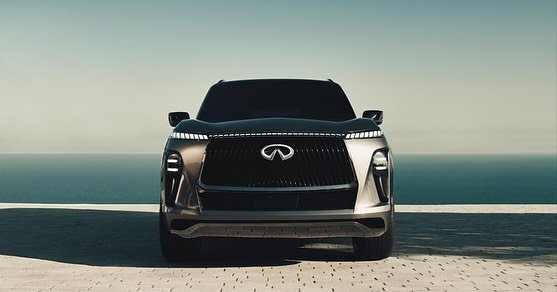 Frontal view of a dark grey Infiniti SUV with LED lighting details. A body of water extends across the horizon under a clear sky.