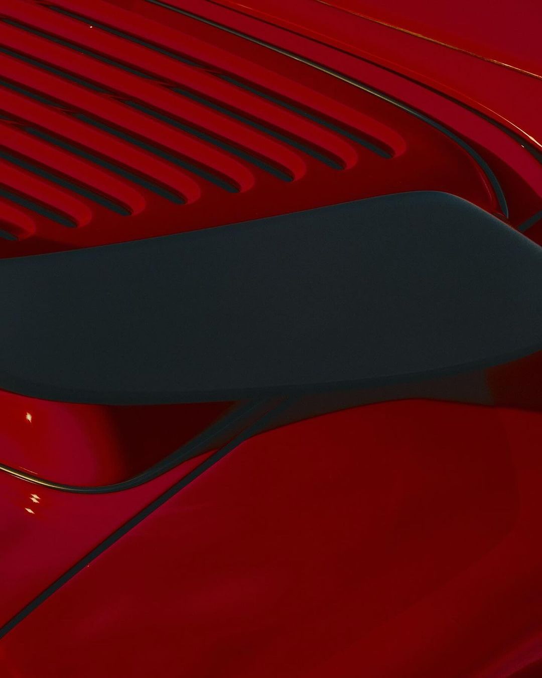 Close-up shot of a red automotive exterior featuring a dark gray vent, showcasing sleek lines and glossy finish in natural lighting.