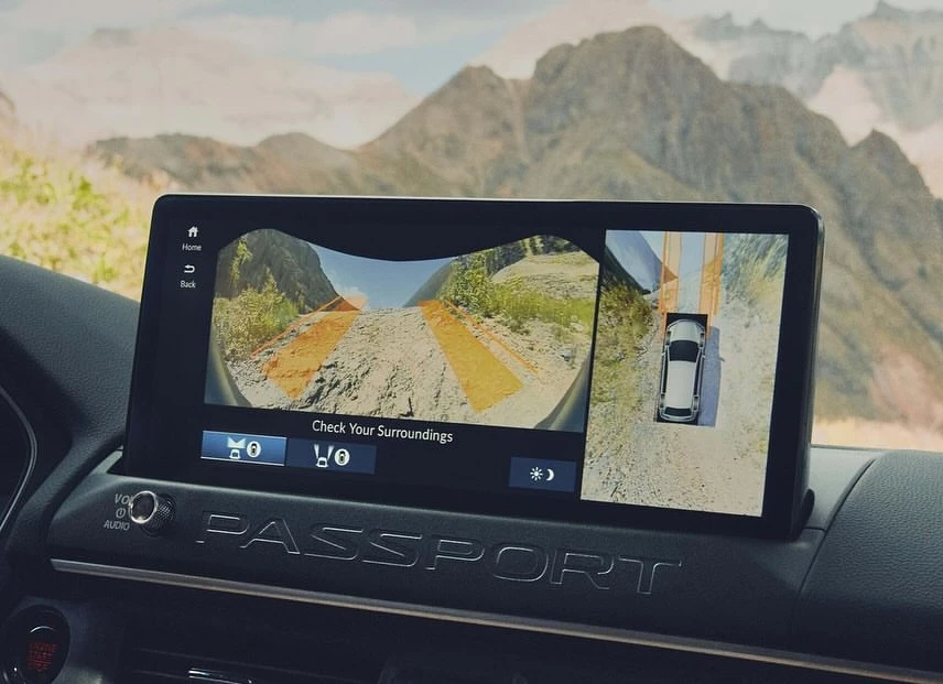 Car dashboard display shows the surrounding environment with mountains in the background. Car feature to check surroundings.