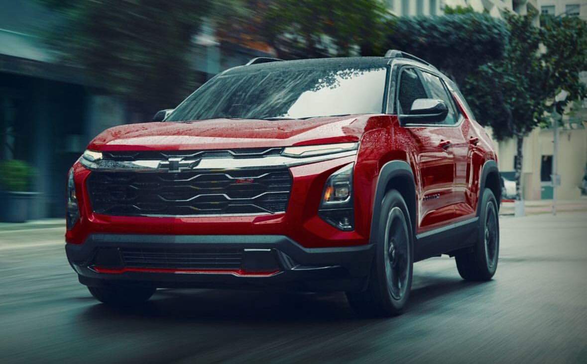 Red Chevrolet SUV driving on a city street. The vehicle is captured at eye-level with blurred motion suggesting it is moving.