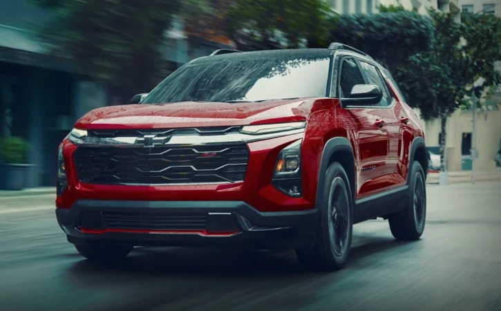 Red Chevrolet SUV driving on a city street. The vehicle is captured at eye-level with blurred motion suggesting it is moving.