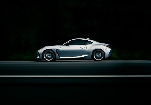 Silver coupe car driving on dark asphalt road. Automotive transportation background with modern design and motion blur effect.