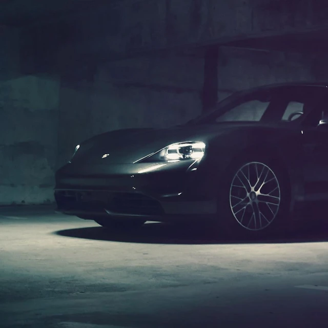 Sleek black electric car parked in a dimly lit concrete garage, spotlighting its design and modern wheel rims.