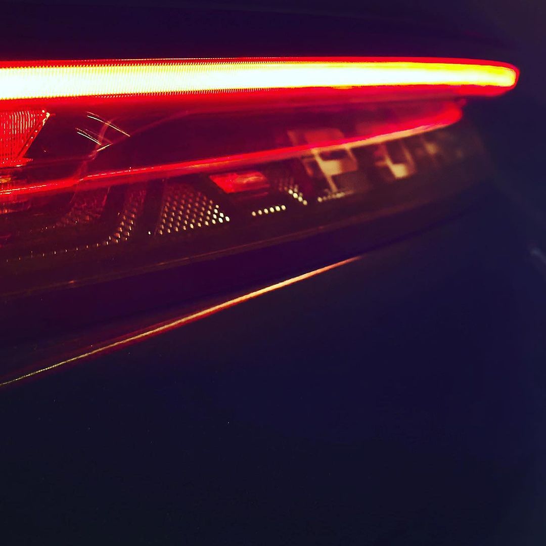Close-up of the red taillight of a car, featuring linear lighting design, with a sleek, modern aesthetic and geometric patterns.