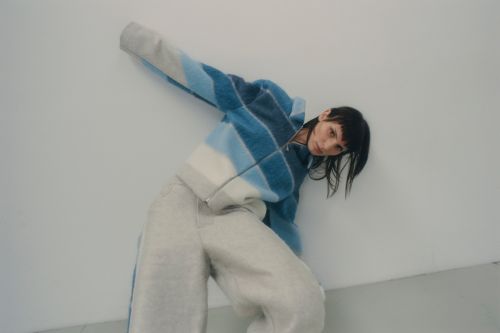 Model in blue striped fleece jacket leaning against a plain white wall shot by David Daub