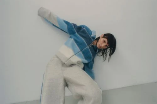 Model in blue striped fleece jacket leaning against a plain white wall shot by David Daub