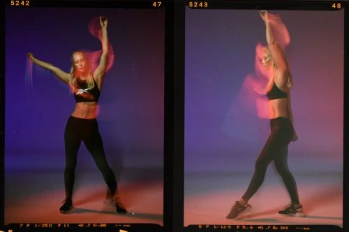 Athletic woman in fitness apparel performs dynamic stretches against a vibrant blue and red background in a dynamic athletic shot.