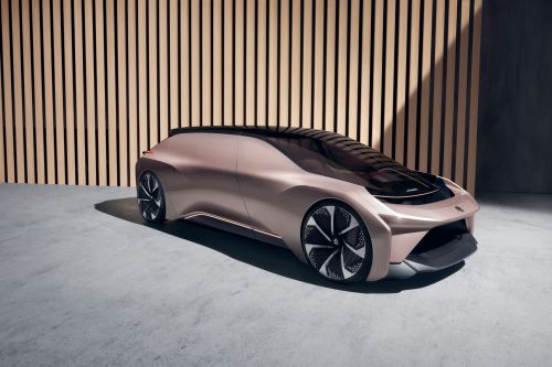 Sleek rose gold electric concept car showcased in a studio setting with modern wood-paneled backdrop and polished concrete floor.