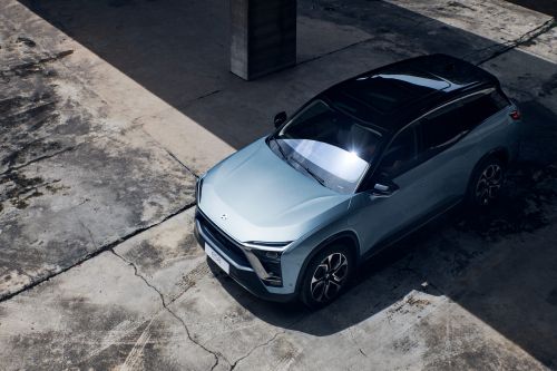 Modern SUV parked on weathered concrete under natural light. The vehicle is light blue with a black roof, casting a distinct shadow.