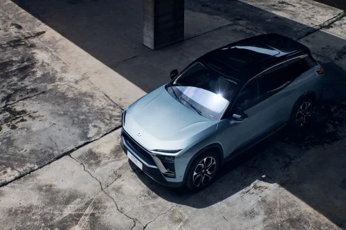 Modern SUV parked on weathered concrete under natural light. The vehicle is light blue with a black roof, casting a distinct shadow.