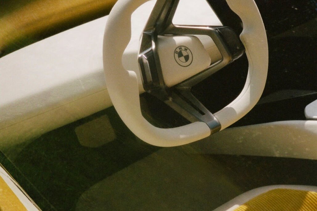Close-up of a white car steering wheel featuring the BMW logo, with a clean, modern design and subtle lighting.