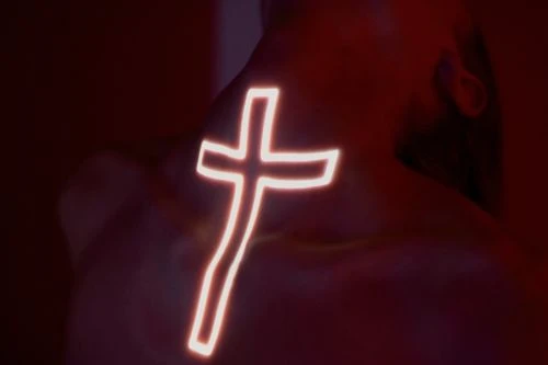 Person with glowing cross on their back in a dimly lit space, creating a dramatic and spiritual image.