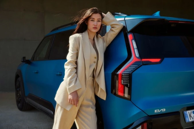 Woman in beige suit leaning against a blue electric SUV by photographer David Daub