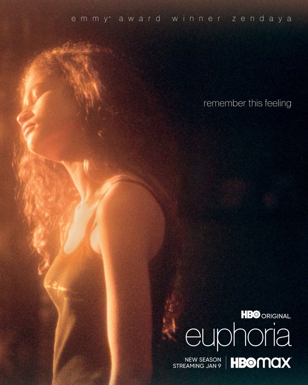 Zendaya is featured in a warm-toned, medium shot for the HBO series 'Euphoria', highlighting her profile in a brightly lit, dark setting.