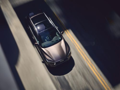 Overhead shot of a luxury vehicle on an asphalt road with double yellow lines, showcasing automotive design and road travel.