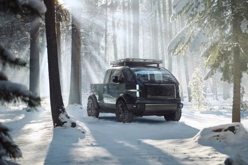 Modern electric pickup truck parked on snow-covered ground in a sunlit winter forest with tall trees and soft natural light.