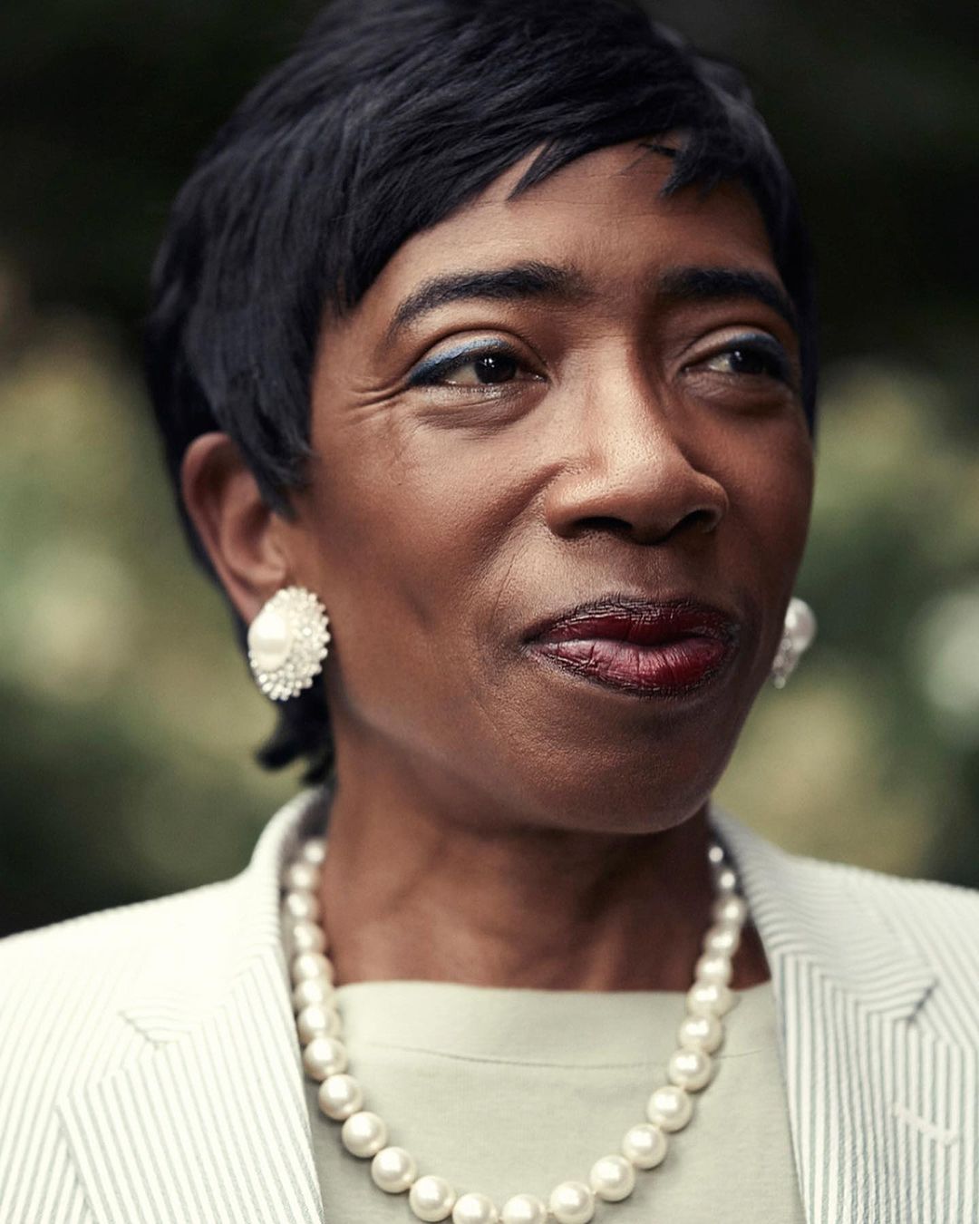 Portrait of a mature Black woman wearing a pearl necklace and white striped blazer by Victoria Will