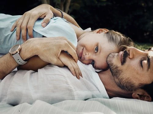 A young girl resting her head on a man's chest while lying down outdoors, captured by photographer Victoria Will.