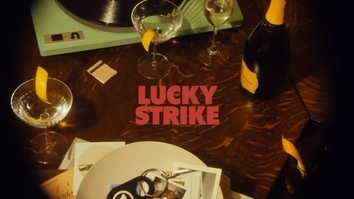 Overhead shot of cocktail glasses with lemon twists, a champagne bottle, vinyl record player, and vinyl records on a wood table.