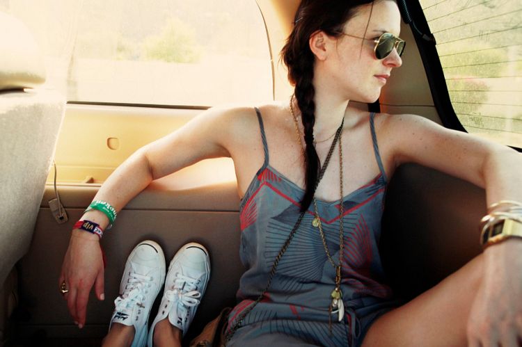Woman in aviator sunglasses wearing a patterned grey romper seated inside a car