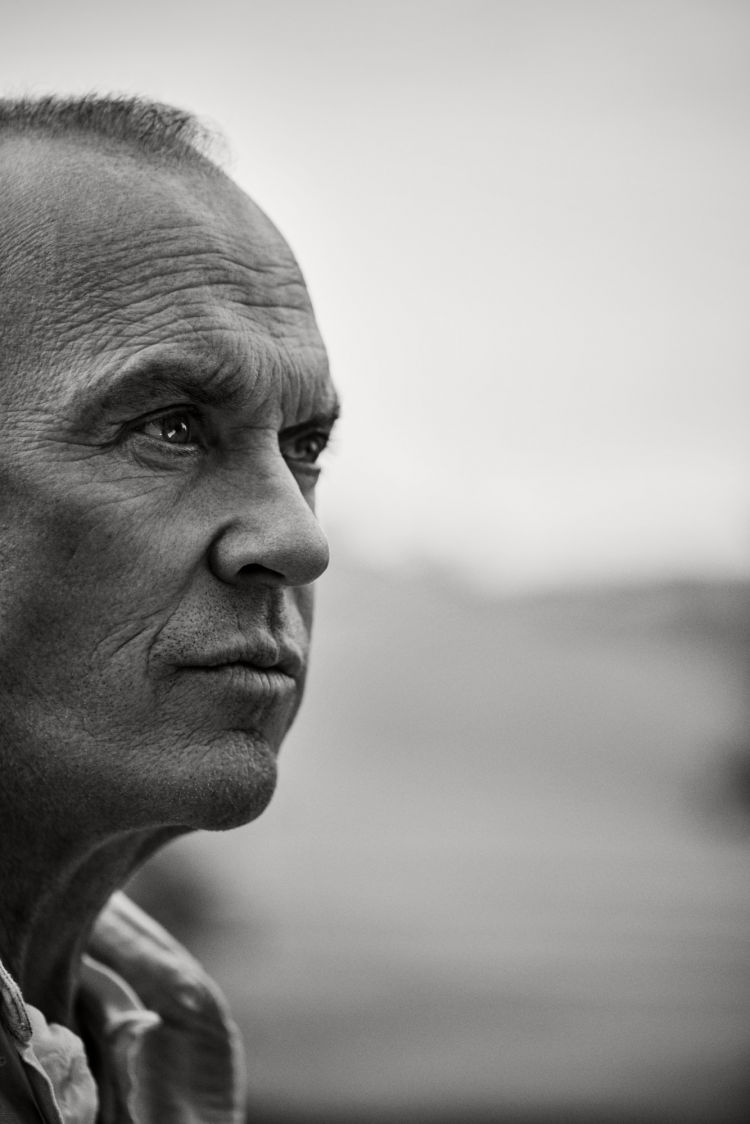 Black and white portrait of a mature adult male looking off-camera, showcasing his facial features and expression against a blurred background.
