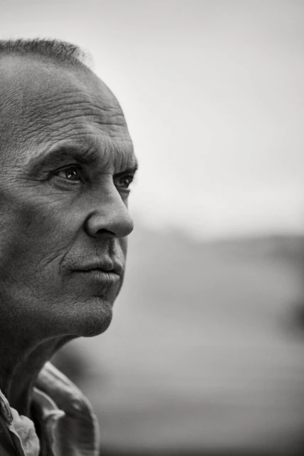 Black and white portrait of a mature adult male looking off-camera, showcasing his facial features and expression against a blurred background.