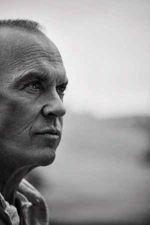 Black and white portrait of a mature adult male looking off-camera, showcasing his facial features and expression against a blurred background.