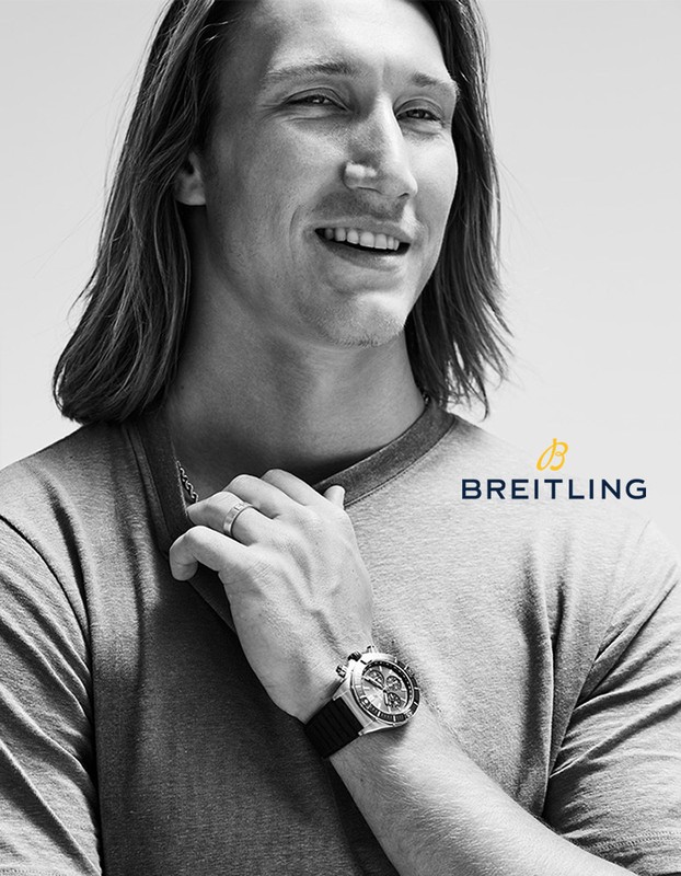 Close up of a handsome adult male model with long hair wearing a silver wristwatch in a black and white advertisement for Breitling.