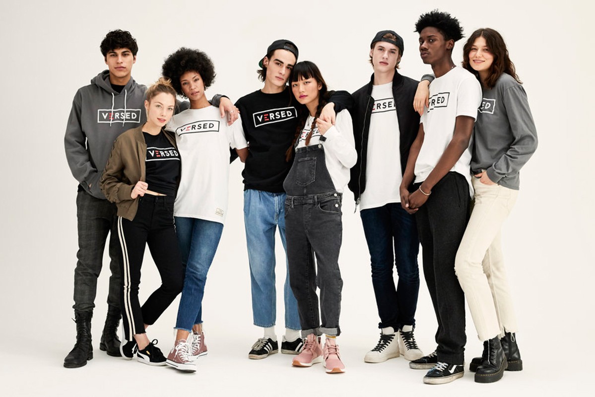 Group of eight multi-ethnic young adult models wearing branded streetwear clothing in a studio shot against a white backdrop.