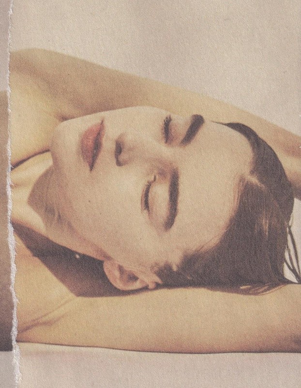 Portrait of a reclining Caucasian adult female with closed eyes and fair skin, illuminated by soft light against a neutral background.