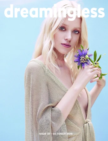 Magazine cover featuring a blonde female model holding a purple passionflower against a light blue background. Text reads: Dreamingless.