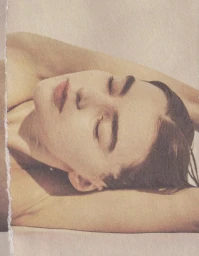 Close up portrait of a woman lying down with eyes closed, featuring hair and makeup styling by Adrienne Herbert.