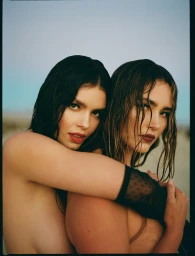 Two women with wet hair embracing closely in a sunlit outdoor portrait by makeup artist Adrienne Herbert in Los Angeles.