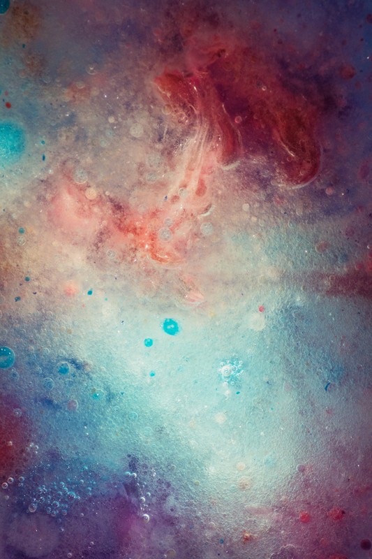 Abstract background with swirls of red, blue, and white color, resembling an underwater scene or celestial nebula.