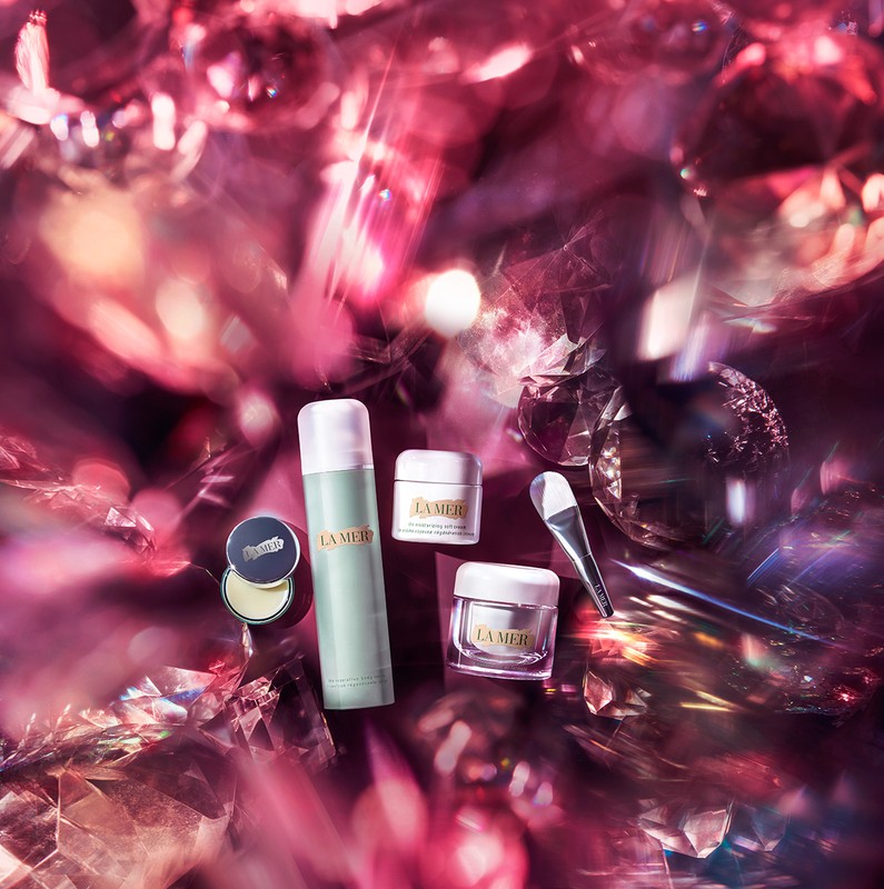 Luxury skincare product assortment by La Mer against an abstract pink background featuring diamonds. Beauty and self-care concept.