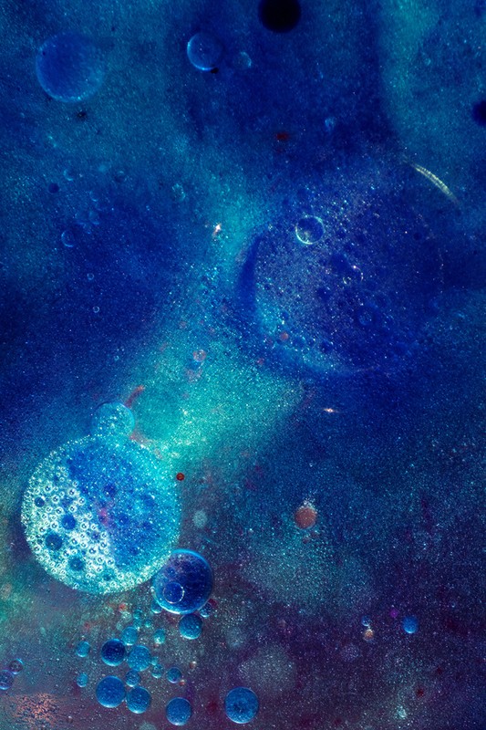 Abstract macro photograph of blue and teal colored bubbles, oil droplets, and liquid, creating a mesmerizing and artistic visual texture.