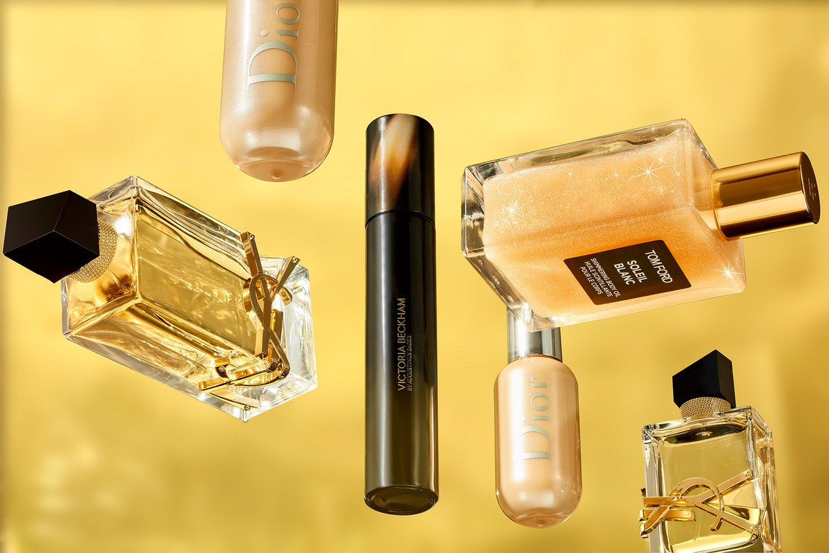 Several bottles of beauty products and perfumes from brands such as Dior, Tom Ford, and YSL on a glossy golden background.