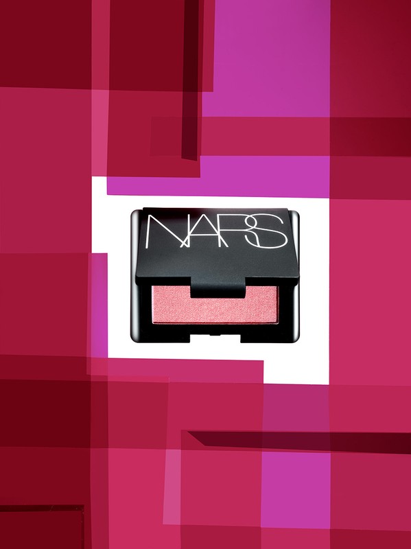 NARS single eyeshadow in black compact case with a pink and magenta abstract background for product shot in a photo studio.
