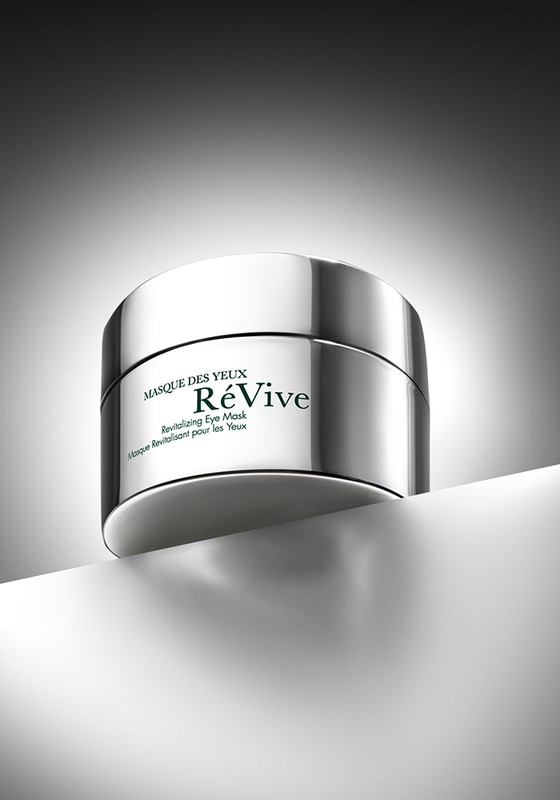 Silver container of ReVive revitalizing eye mask product on white surface with gray background in a product shot for beauty and skincare.