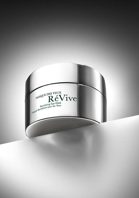 Silver container of ReVive revitalizing eye mask product on white surface with gray background in a product shot for beauty and skincare.