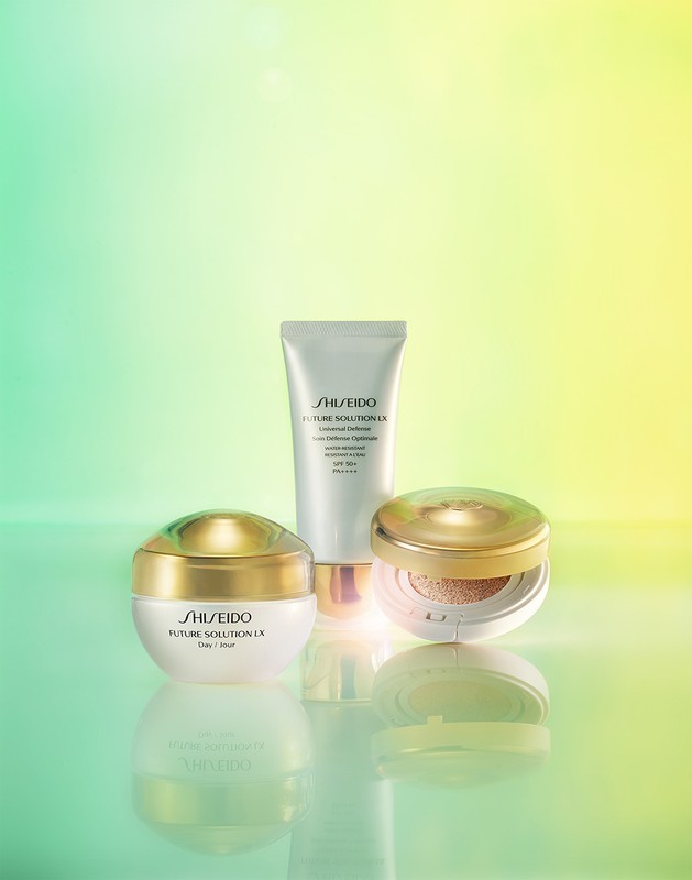 Cosmetic product presentation with Shiseido Future Solution LX cream, cleanser, and sunscreen, staged on a reflective surface with a pastel background.