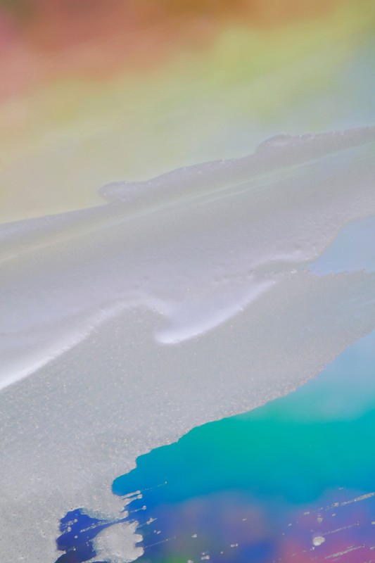 Abstract background image featuring flowing textures with an iridescent color palette of pink, yellow, grey, blue, and teal.