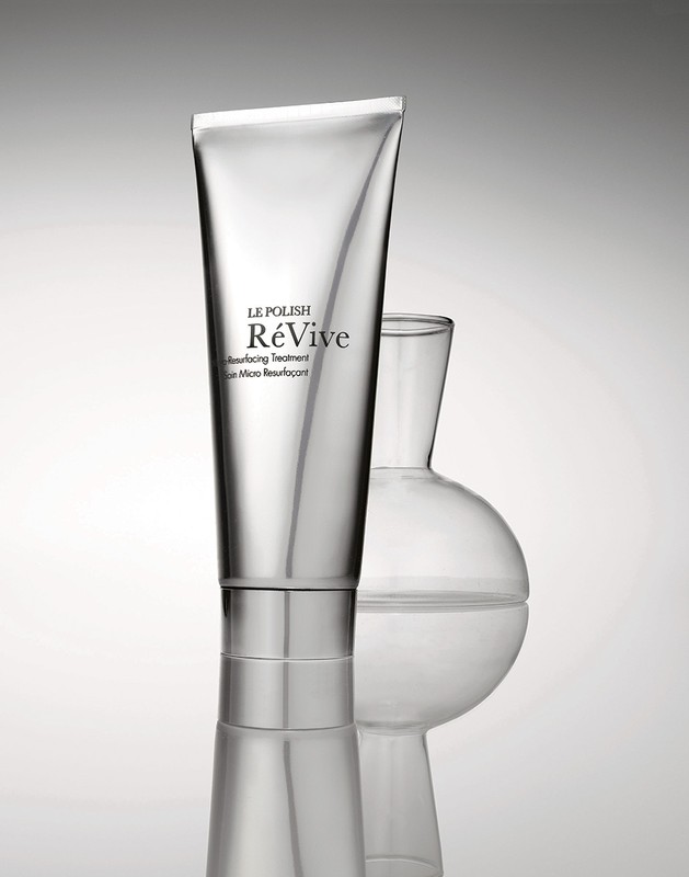 Silver tube of Le Polish ReVive skin resurfacing treatment alongside a transparent glass lab flask against a gradient background.