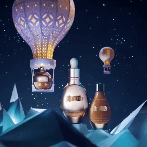 La Mer skincare products displayed with hot air balloon and mountain design against dark blue starry background in a beauty product still life.
