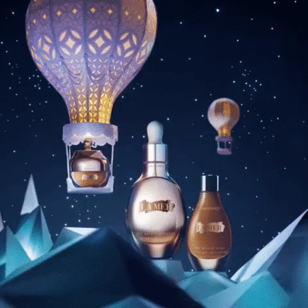 La Mer skincare products displayed with hot air balloon and mountain design against dark blue starry background in a beauty product still life.