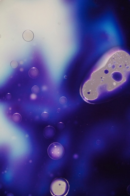 Abstract macro image with fluid-like forms, bubbles, and vibrant color gradients of blue, purple, and white, creating a dreamy, ethereal effect.